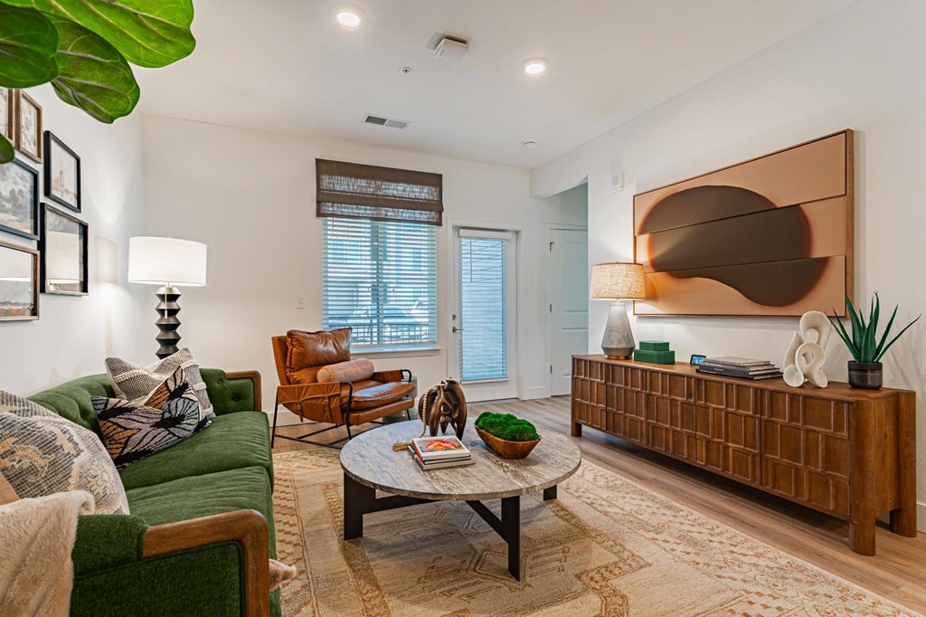 A living room with a green couch, a brown coffee table, and a large abstract painting on the wall.