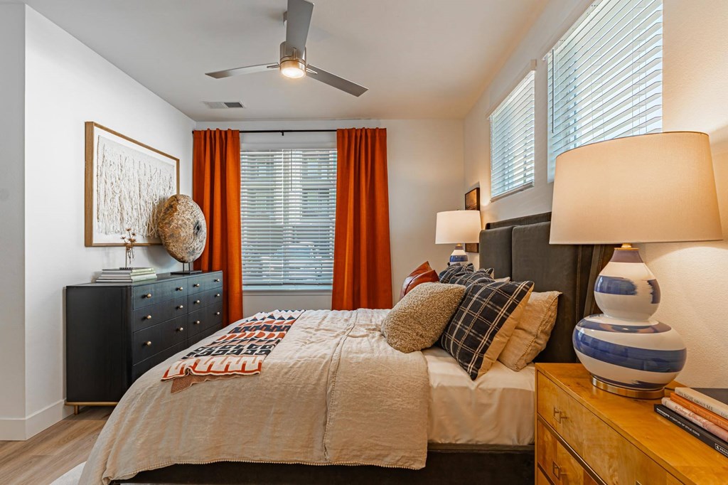 A bedroom with a bed, dresser, and ceiling fan.