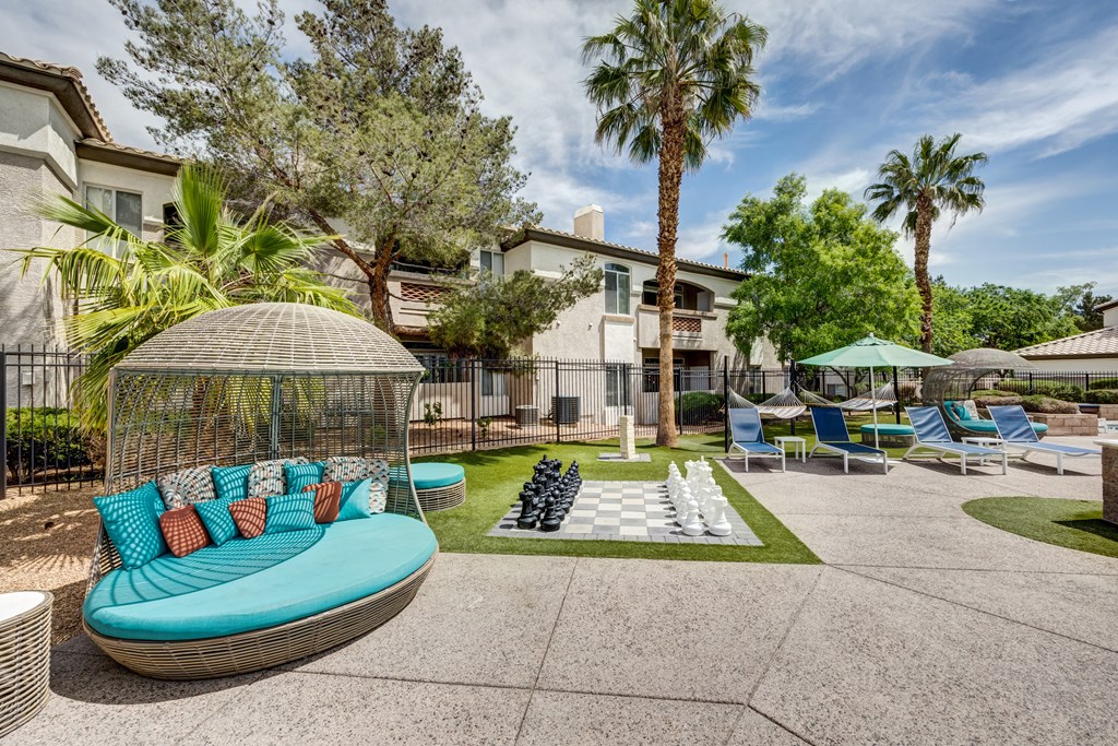 an outdoor lounge area with a gazebo, lounge chairs and giant chess set