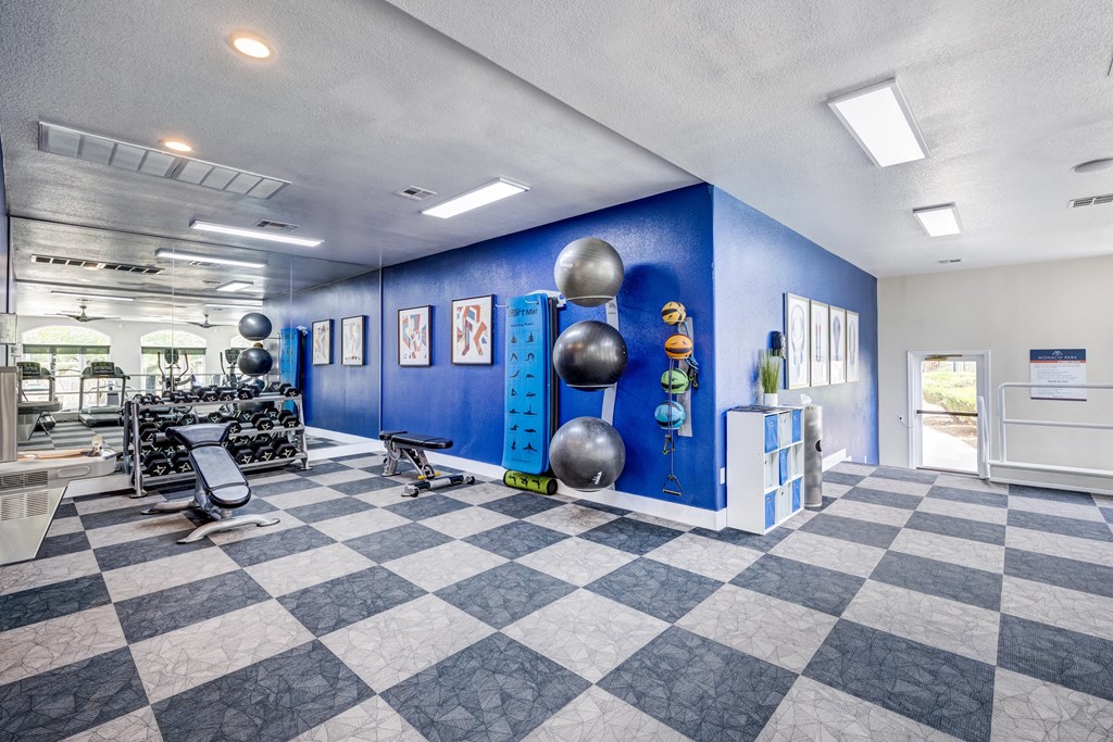 a spacious fitness center with a checkered floor and blue walls