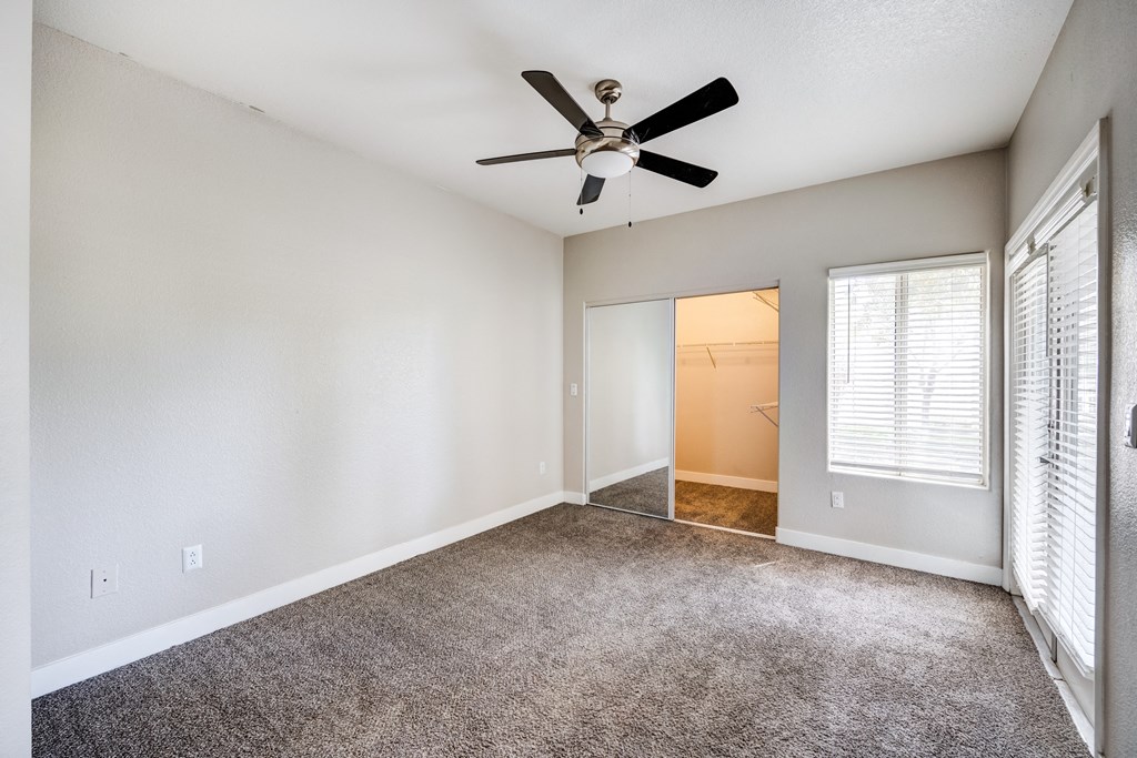 a bedroom with white walls and a ceiling fan