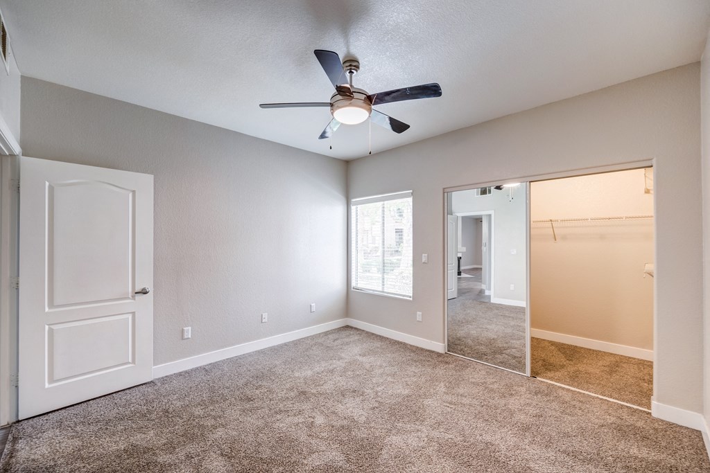 an empty bedroom with a ceiling fan