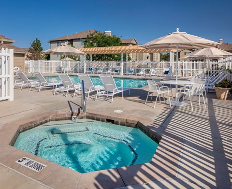 A pool with a hot tub and sun loungers.