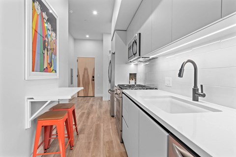 A kitchen with a white counter top and a painting on the wall.