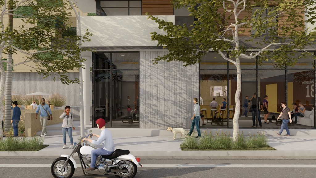 A man in a white shirt and blue jeans is riding a motorcycle on a city street.