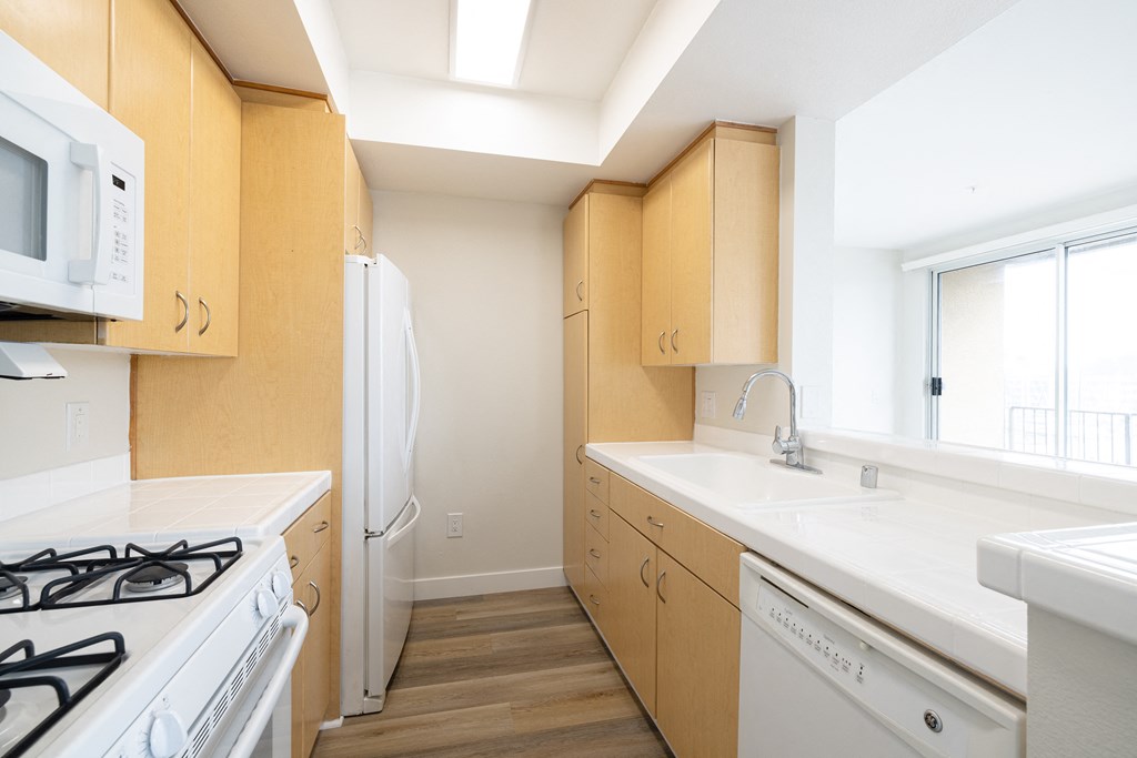A kitchen with white appliances and wooden cabinets.