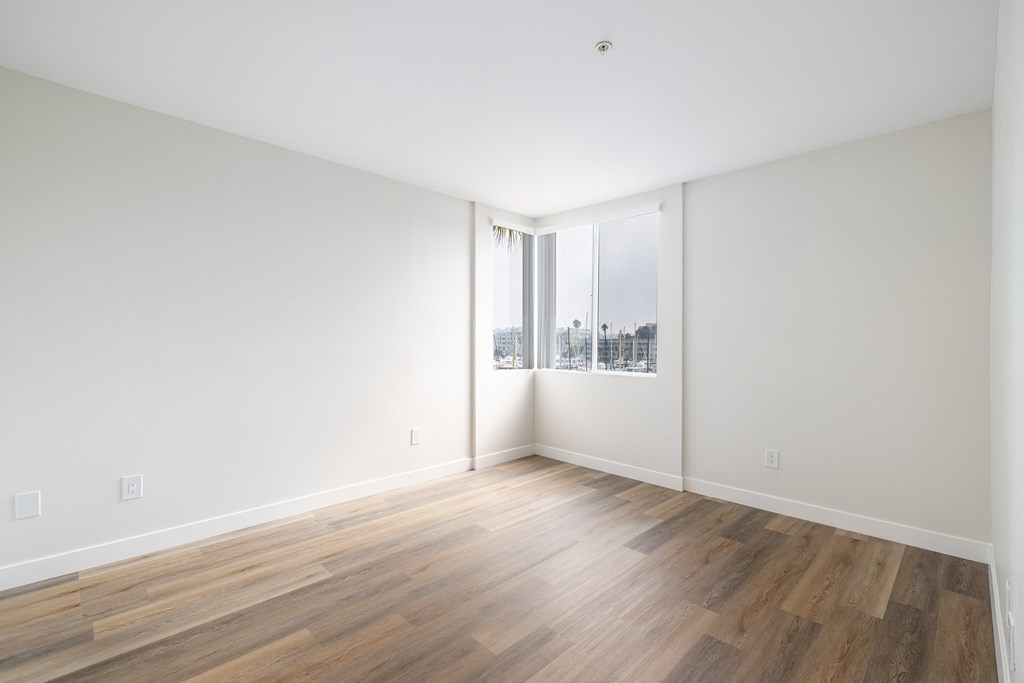 A room with wooden flooring and a window overlooking a cityscape.