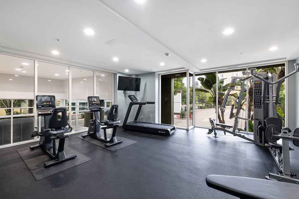 A spacious gym with a variety of equipment including treadmills, elliptical machines, and weight machines.