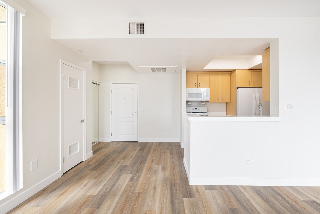 A kitchen with white walls and wooden floors.
