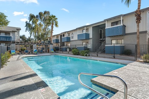 A swimming pool surrounded by a fence and palm trees.