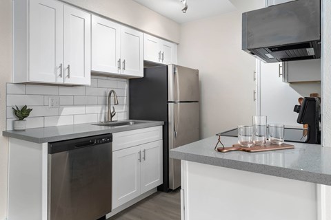 A kitchen with white cabinets and a black refrigerator.