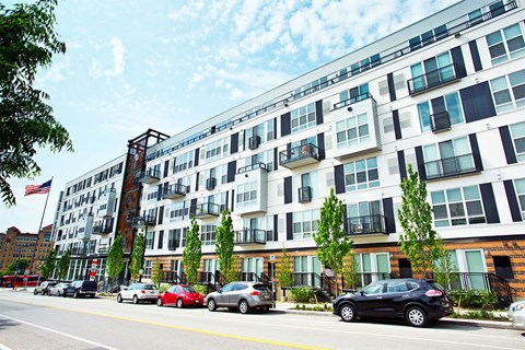 A black car is parked on the side of the road in front of a building.