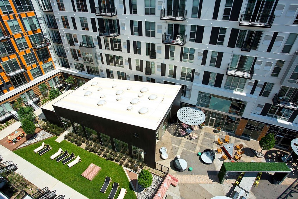 A modern building with a white roof and a green lawn in front.