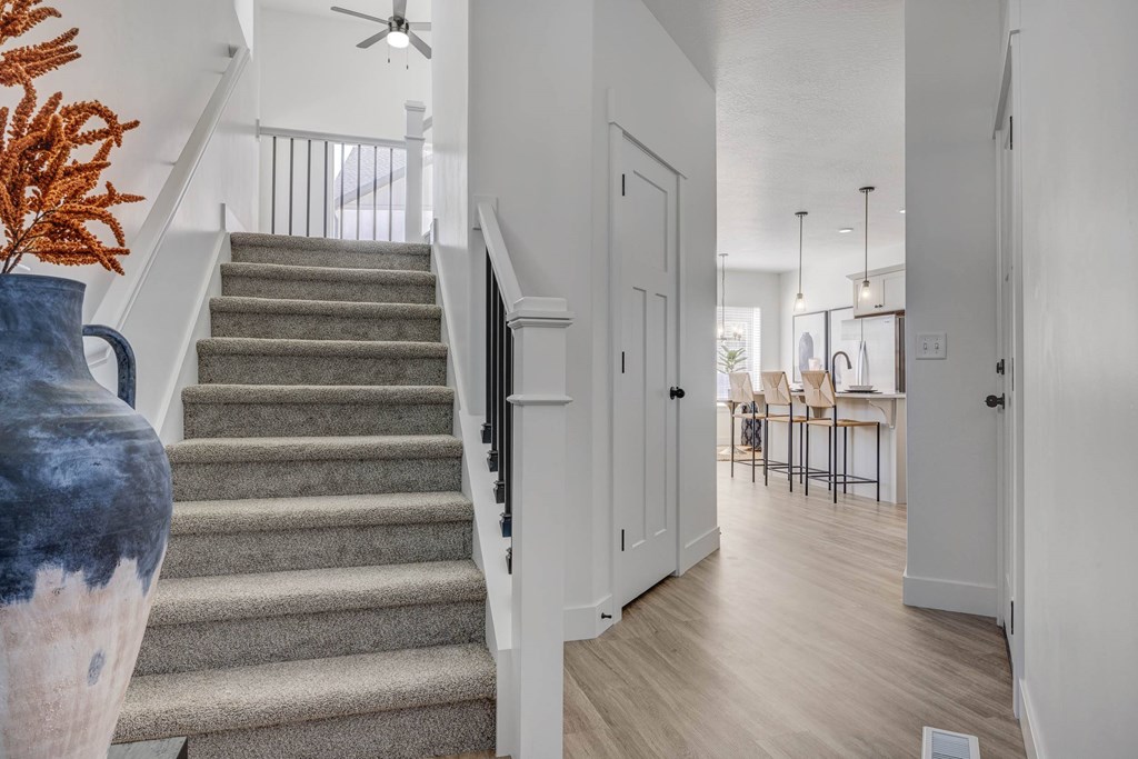 A hallway with a staircase and a vase with orange flowers.