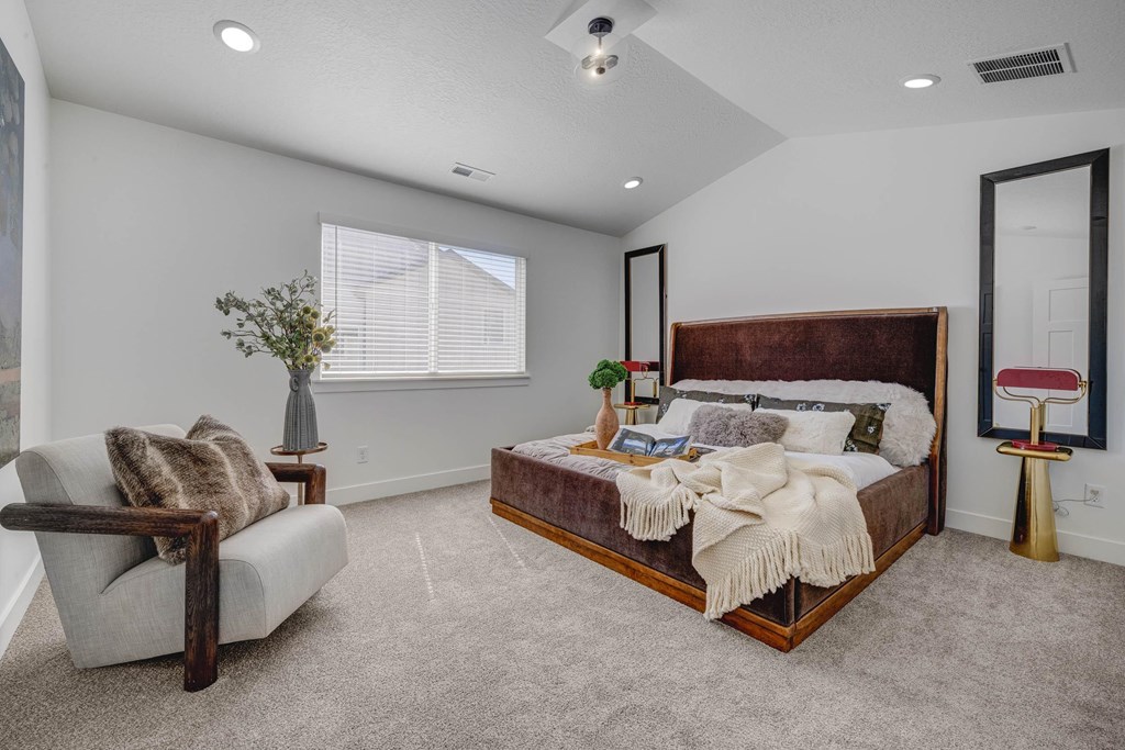 A bedroom with a large bed and a chair.