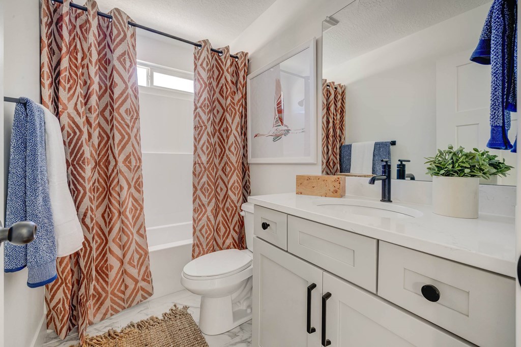A bathroom with a toilet, sink, and shower curtain.
