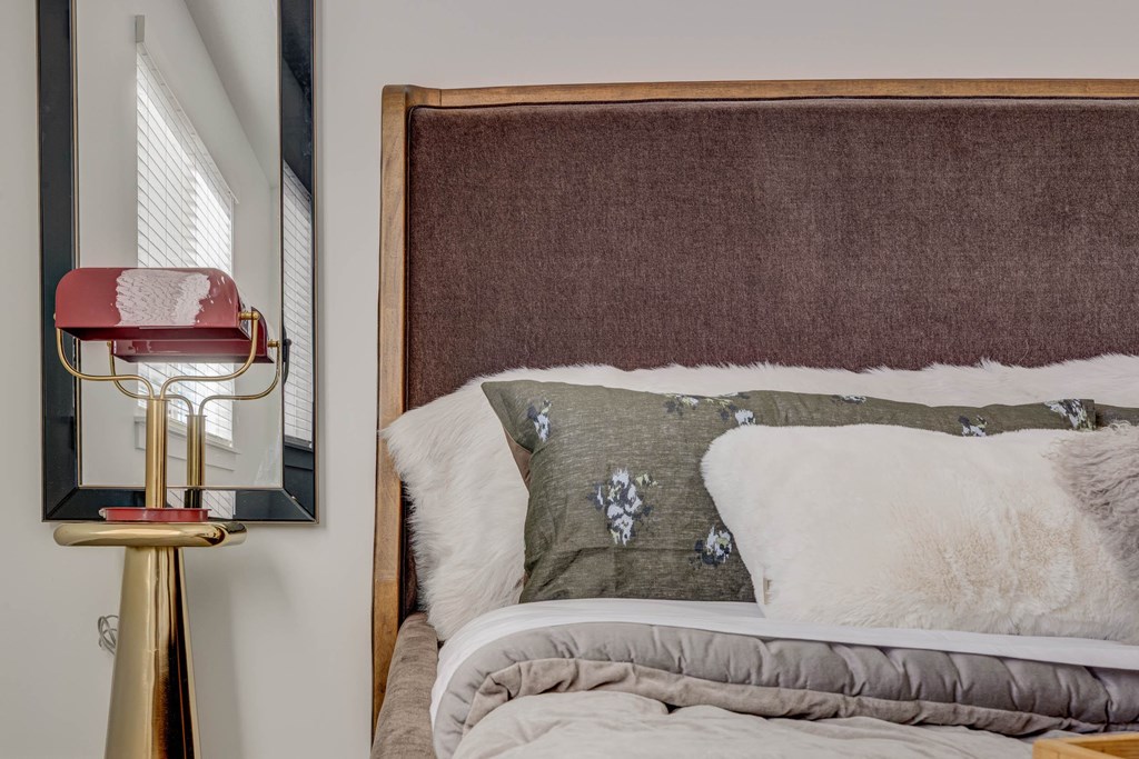 A bed with a grey comforter and a pillow with a grey and white design.