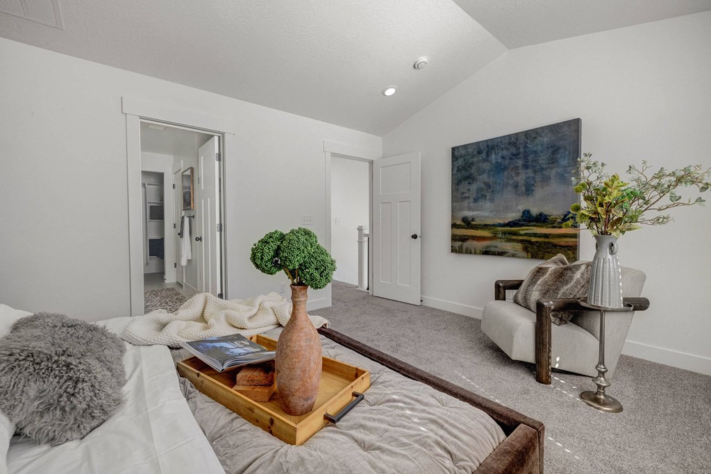 A living room with a grey couch and a painting on the wall.