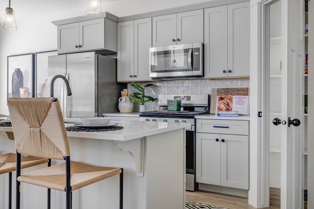 A kitchen with a white countertop and grey cabinets.