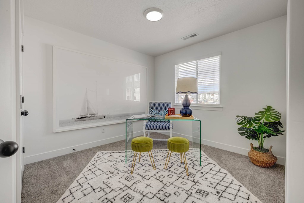 A room with a white rug and a green stool.
