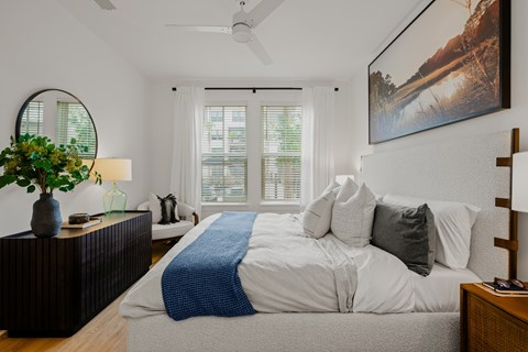 A bedroom with a large bed and a painting on the wall.