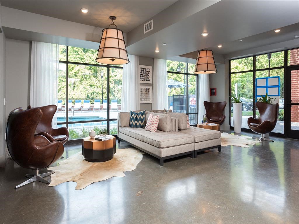 a living room with a couch and chairs and large windows