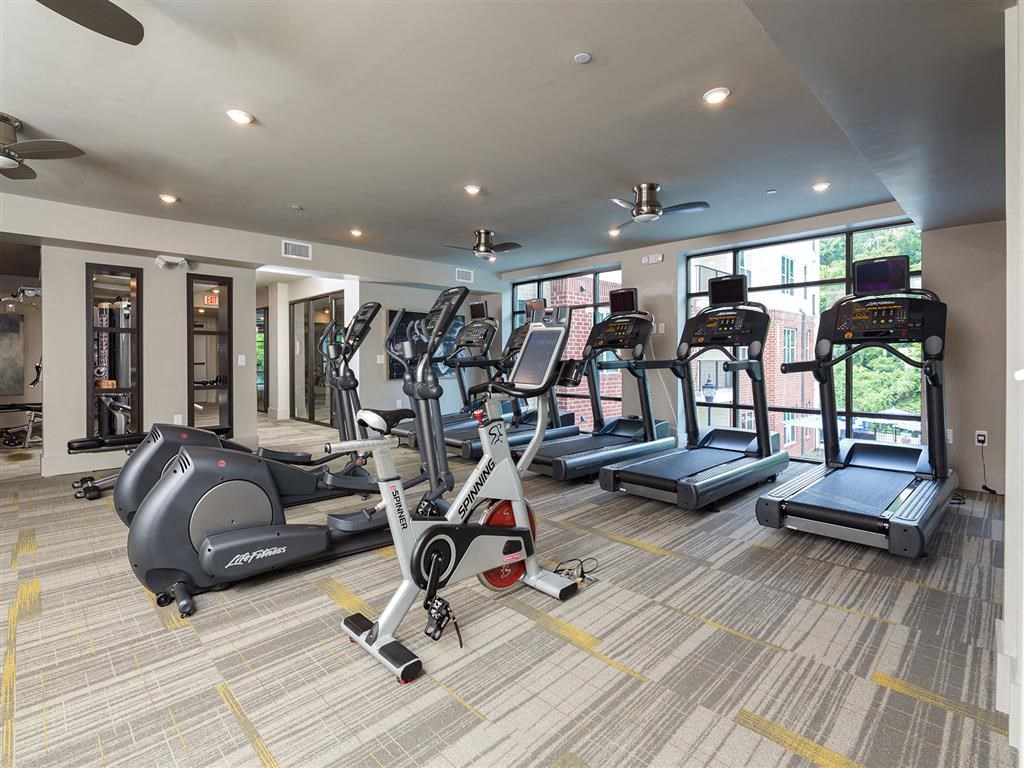 a gym with cardio equipment and windows in a building