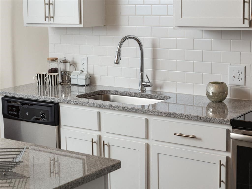 a white kitchen with granite counter tops and a sink