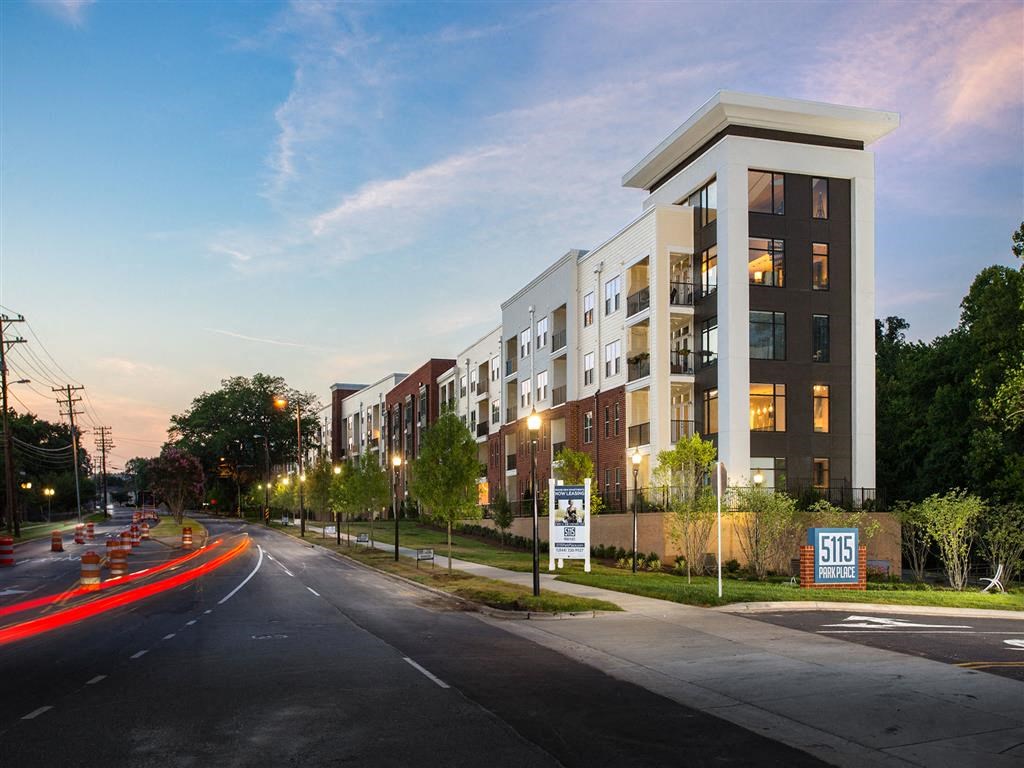 a rendering of an apartment building at dusk on a city street