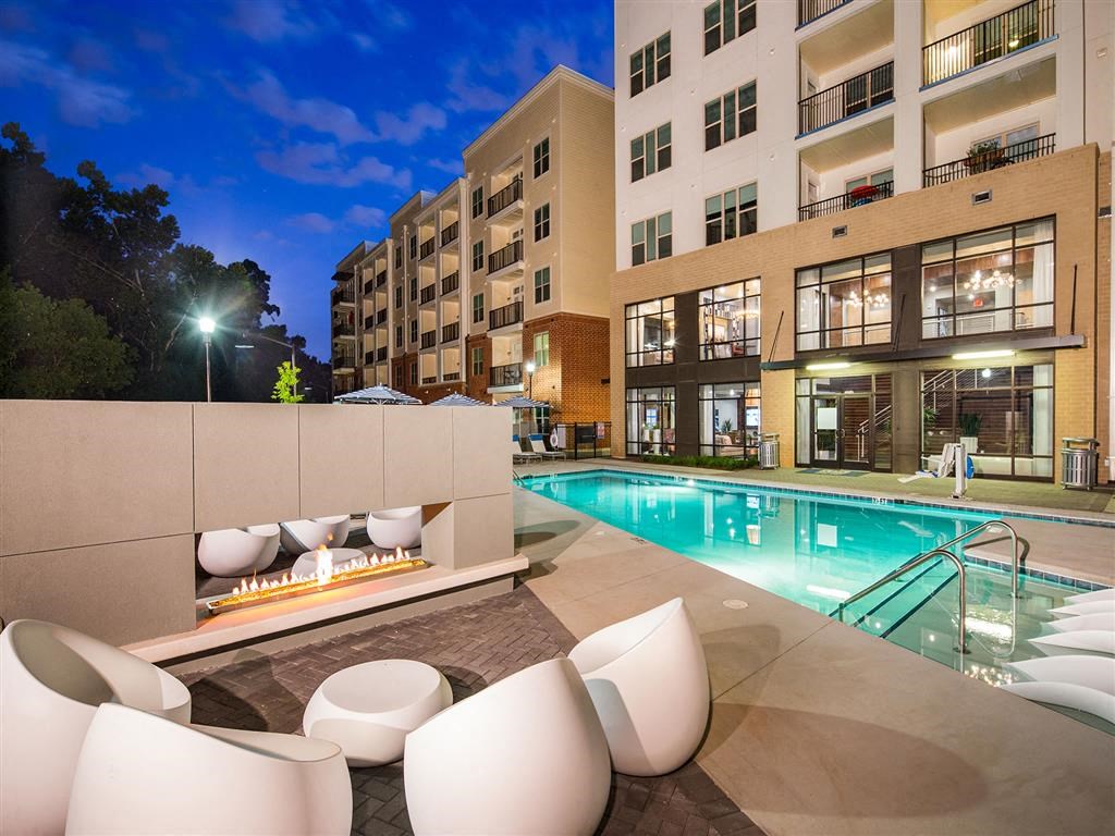 a swimming pool with chairs and a fire pit at night