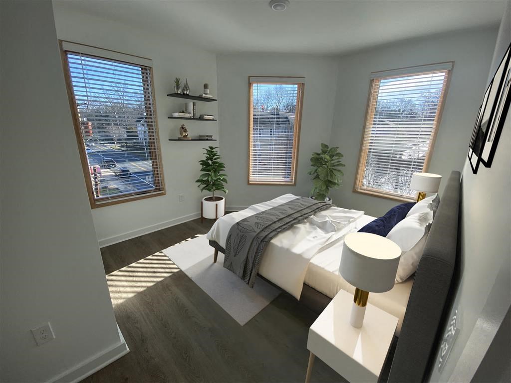 a bedroom with three windows and a bed