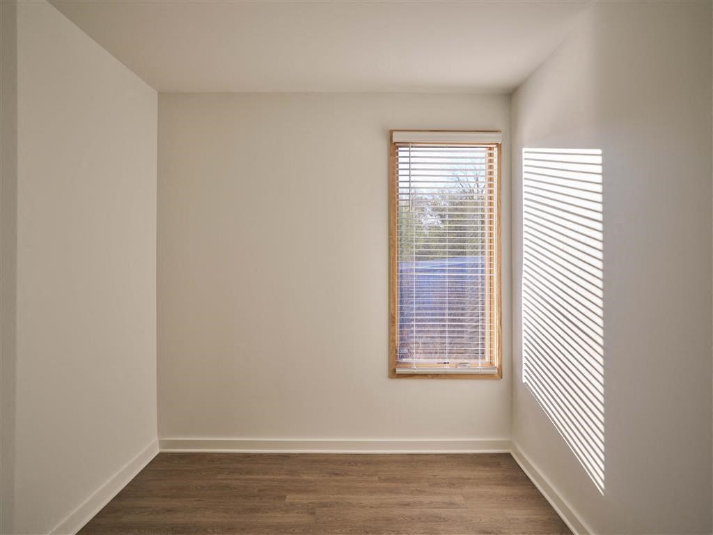 a bedroom with two windows and a wooden floor