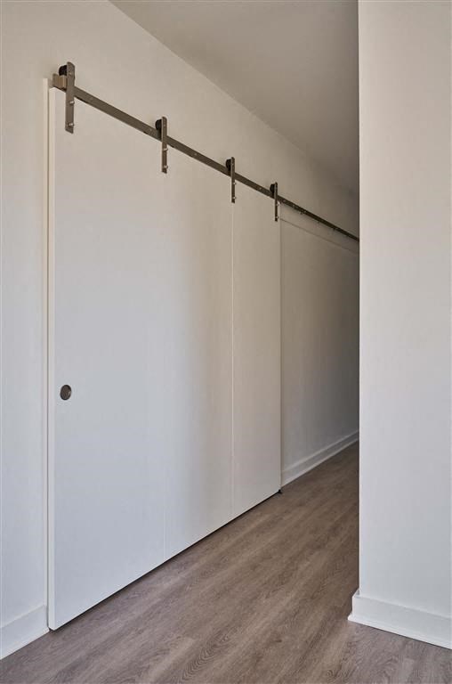 a room with a wooden floor and a white wall with a sliding door