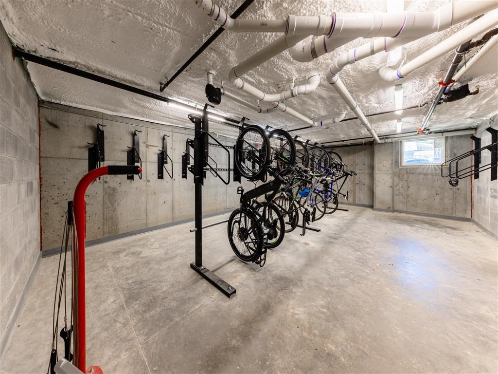 a collection of bikes in a basement room with pipes and wiring