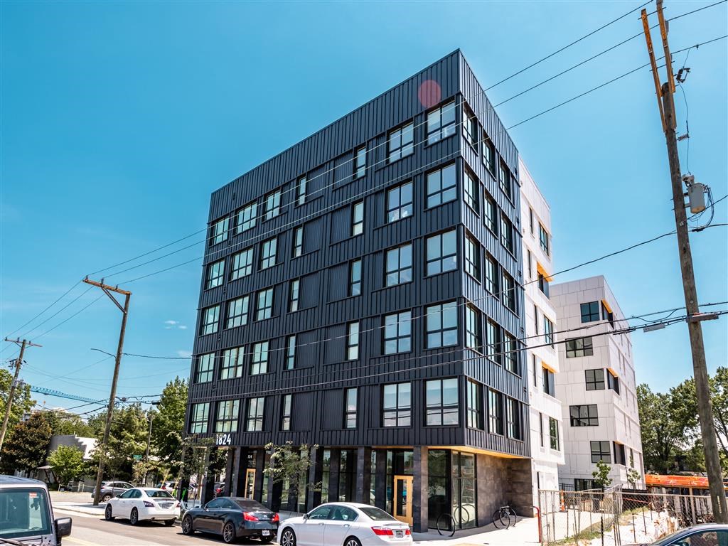 a tall black building with cars parked in front of it