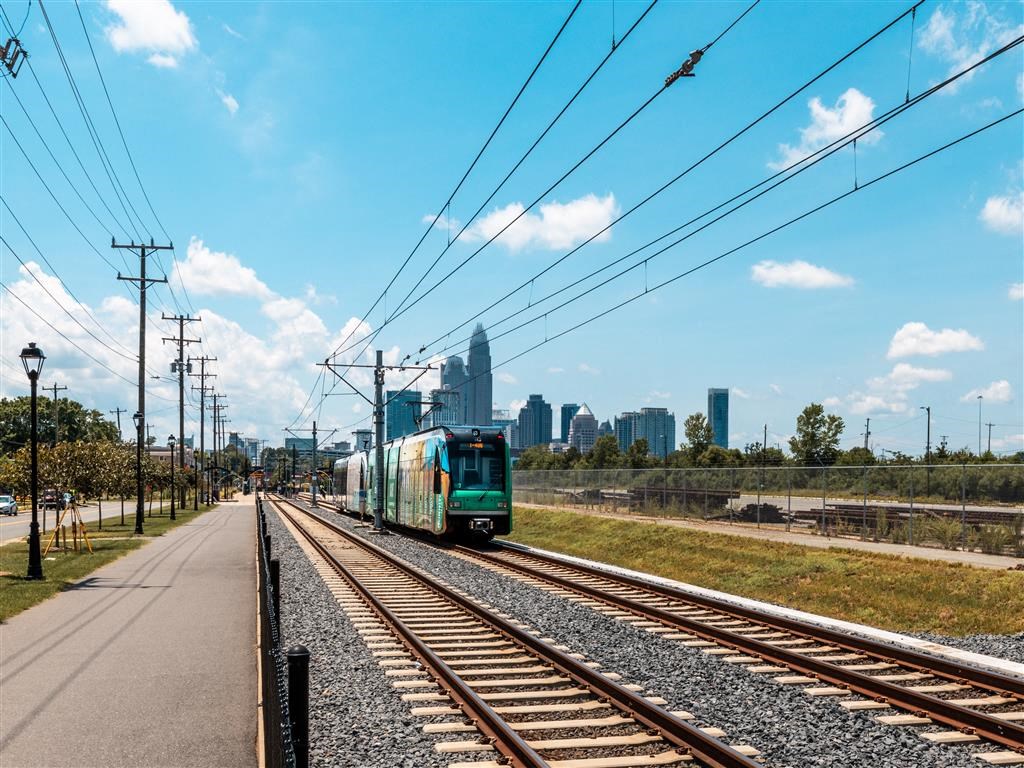 a green train on the tracks with a city in the background