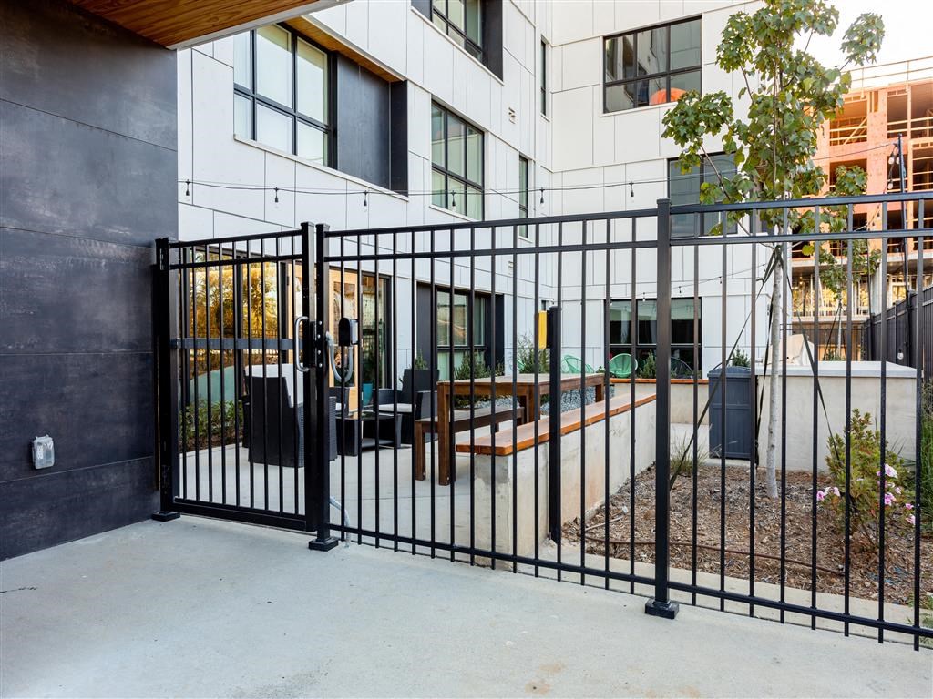 the gate to an apartment building with a patio in front of it