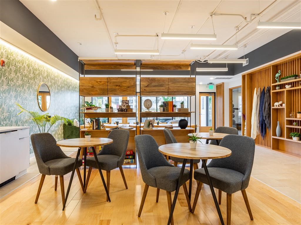 a dining room with tables and chairs and a kitchen in the background