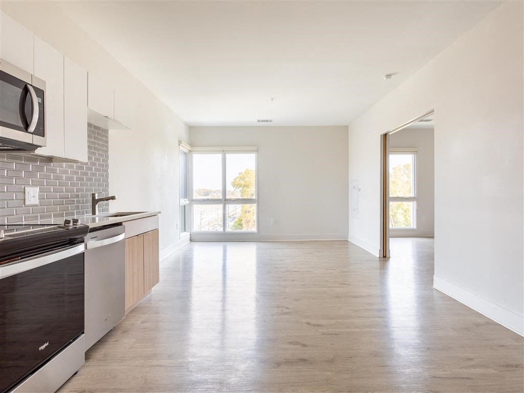 an empty kitchen and living room with white walls and wood floors