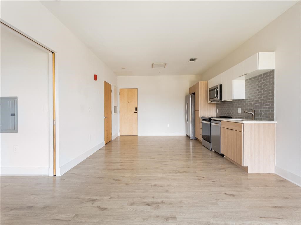 an empty living room and kitchen with a wood floor