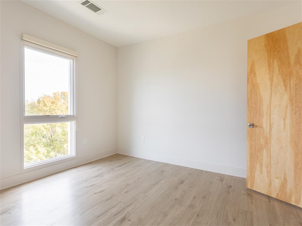 an empty room with a wooden door and a window