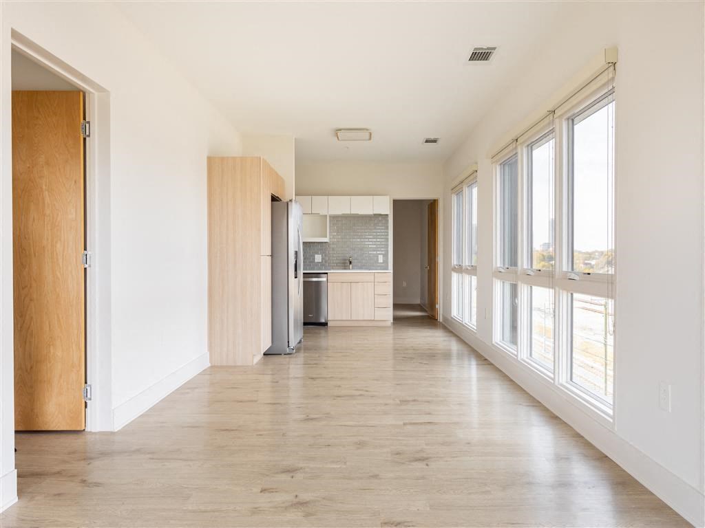 a large empty room with a kitchen and windows