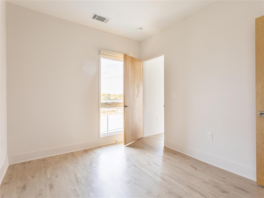 an empty room with white walls and wood floors