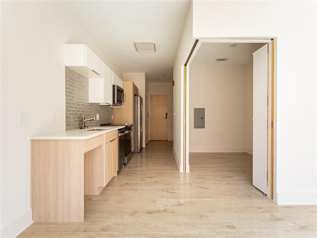 an empty room with a kitchen and an open door