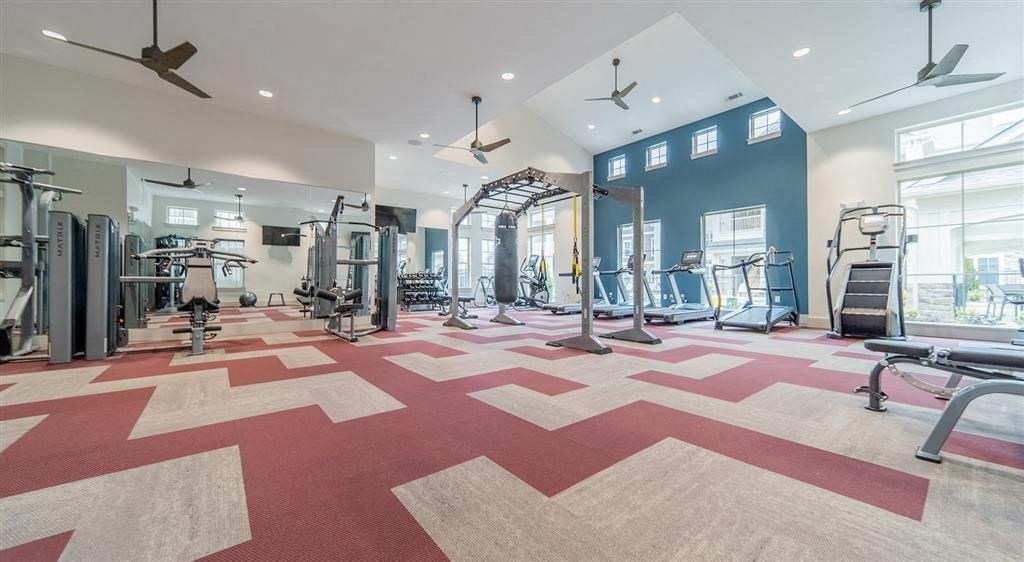 a spacious fitness center with exercise equipment and windows