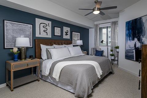 A bedroom with a large bed and a ceiling fan.