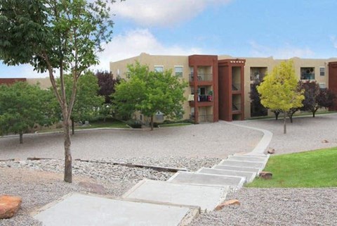 a building with a sidewalk and trees in front of it