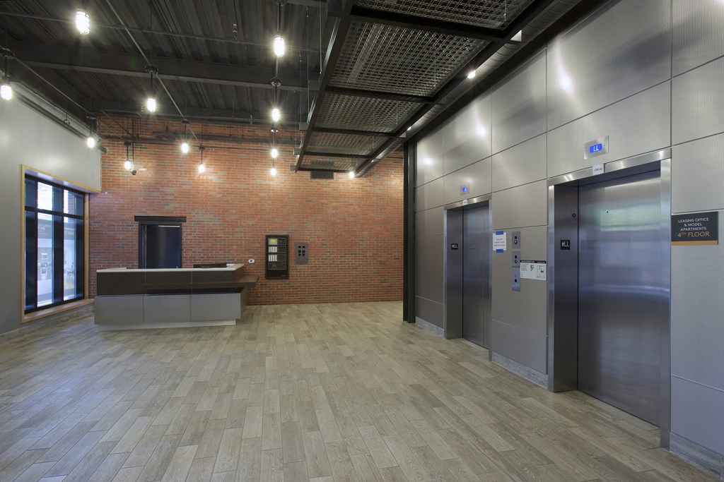 a lobby with elevators and a reception desk and a brick wall