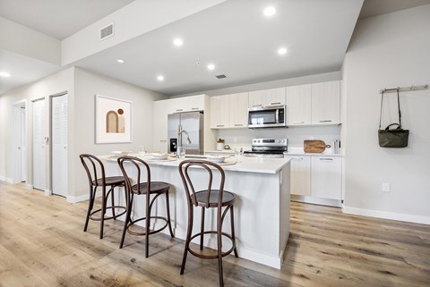 A kitchen with a white island and bar stools.