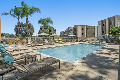 A resort style pool with lounge chairs and umbrellas.